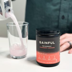 a person pouring a mixed serving of gainful stim free pre workout into a glass