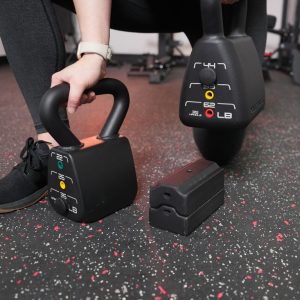 an athlete with two powerblock adjustable kettlebells showing how the weight system works