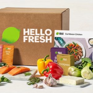 a meal kit box from Hello Fresh with different food ingredients in the foreground, such as salmon, bell peppers, garlic, bok choy, a carton of chickpeas, and more