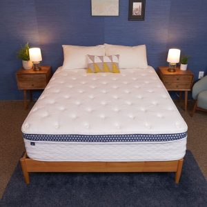 A mattress on a wooden bed frame in a stylish bedroom with blue walls and bedside tables with lamps.