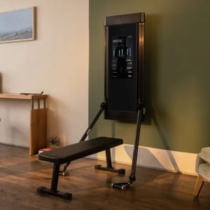 a weight bench on the floor in front of a tonal machine mounted on the wall