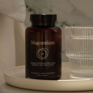 A bottle of Lifeforce Magnesium beside a cup of water.