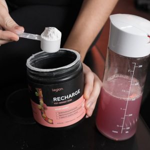 legion post workout drink recharge containing creatine being scooped and mixed by a product tester