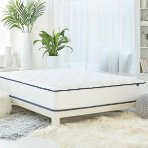 Helix Dawn mattress in a bright, minimalist bedroom, showcasing a white mattress with a blue trim on a white bed frame.