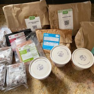 Green Chef meal kit contents spread out on a counter, including packaged ingredients and meal preparation bags.