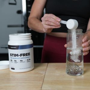 person pouring scoop of transparent labs stim free pre workout into shaker bottle