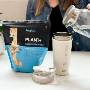 Tester pouring water next to a package of Legion Plant+ protein powder