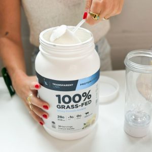 A person scooping a tub of French Vanilla Transparent Labs 100% Grass-Fed Whey Protein Isolate