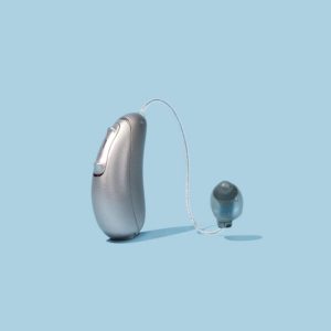 Audicus Omni hearing aid with silver finish on blue background