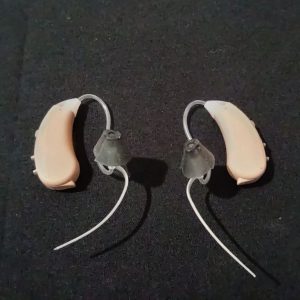 Compact MDHearing aids with silicone ear tips on a dark background